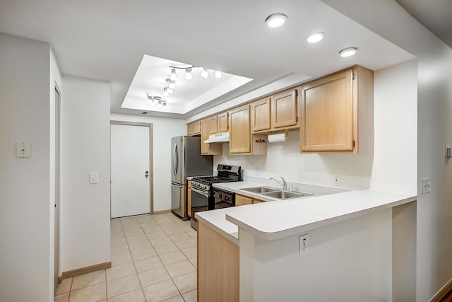 kitchen featuring a raised ceiling, light countertops, appliances with stainless steel finishes, light brown cabinets, and a sink