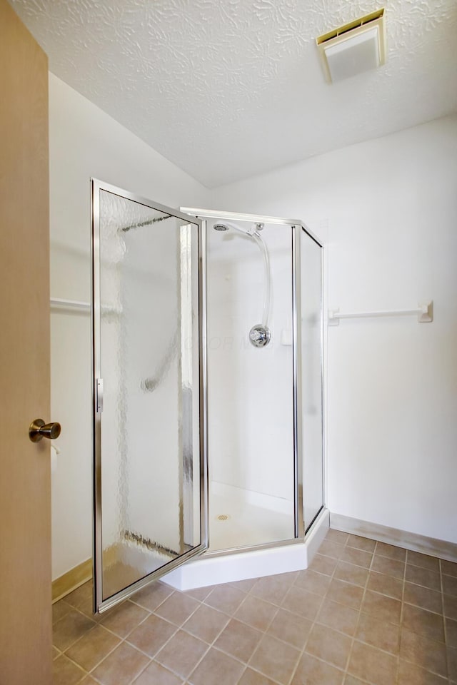 bathroom with a stall shower, a textured ceiling, and tile patterned floors