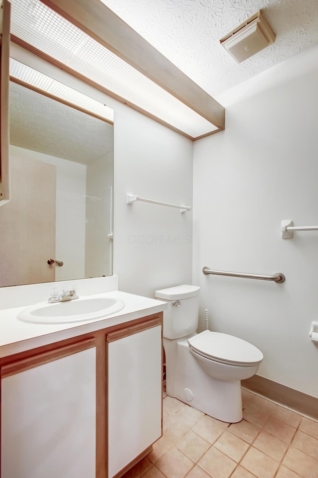 bathroom featuring vanity, a textured ceiling, toilet, and tile patterned floors