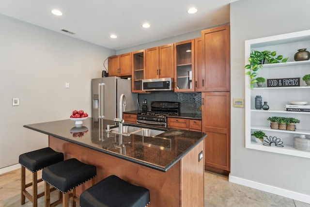 kitchen featuring tasteful backsplash, visible vents, appliances with stainless steel finishes, brown cabinetry, and a kitchen breakfast bar