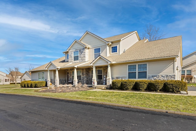 craftsman house with a porch, stone siding, roof with shingles, and a front lawn