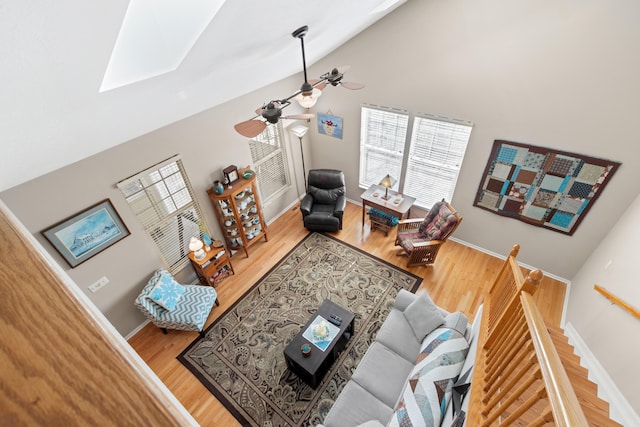 living area with a ceiling fan, baseboards, high vaulted ceiling, and wood finished floors