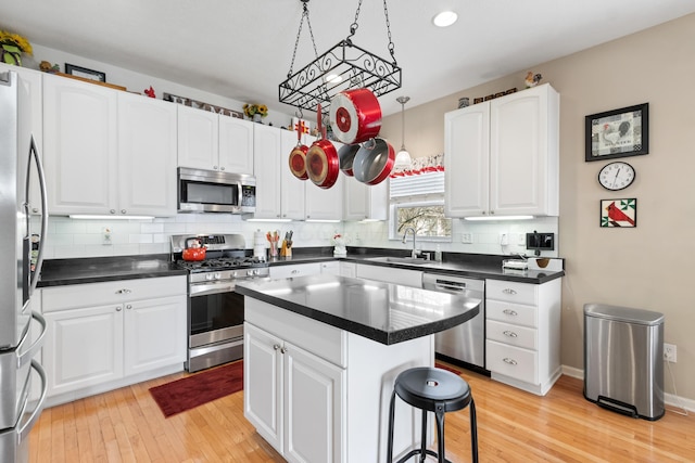 kitchen featuring appliances with stainless steel finishes, dark countertops, a kitchen island, and white cabinets