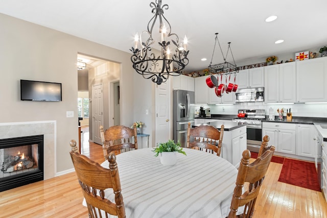 dining space featuring light wood-type flooring, recessed lighting, and a premium fireplace