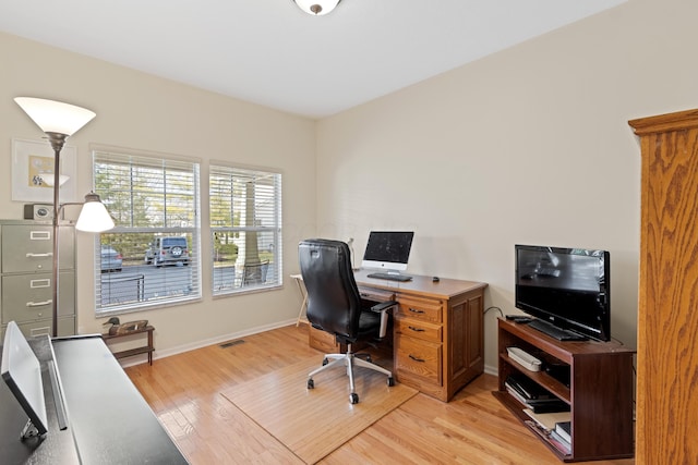 office space with light wood finished floors, visible vents, and baseboards