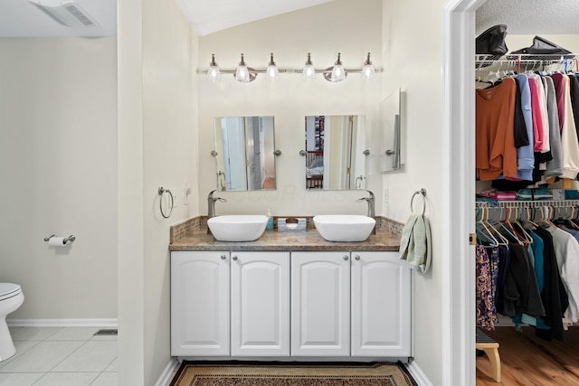 bathroom with tile patterned floors, a sink, toilet, and double vanity