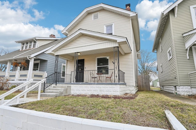 view of front facade featuring a porch, a chimney, and a front yard