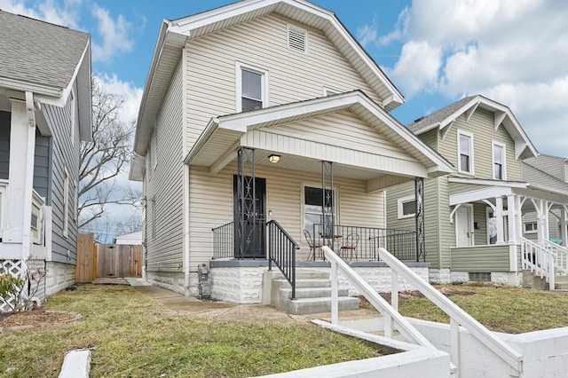 view of front facade featuring covered porch, fence, and a front yard