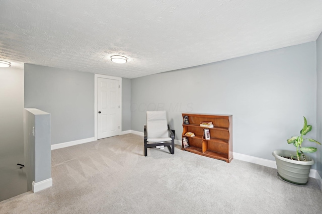 living area with carpet flooring, a textured ceiling, and baseboards