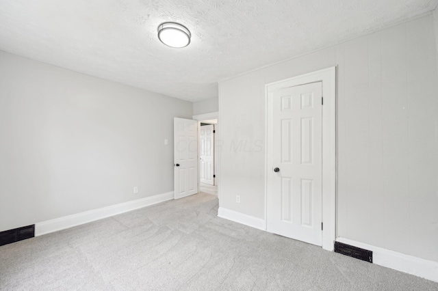 empty room with baseboards, carpet, visible vents, and a textured ceiling