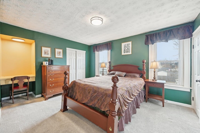 carpeted bedroom with a textured ceiling, a closet, and baseboards