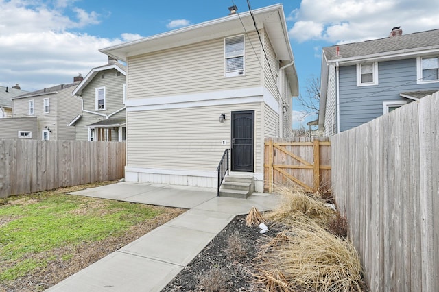 back of property with entry steps, a fenced backyard, and a patio