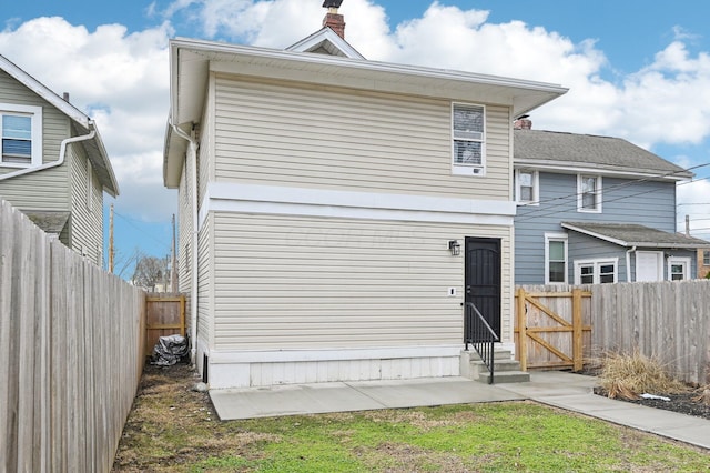 rear view of property featuring entry steps and a fenced backyard