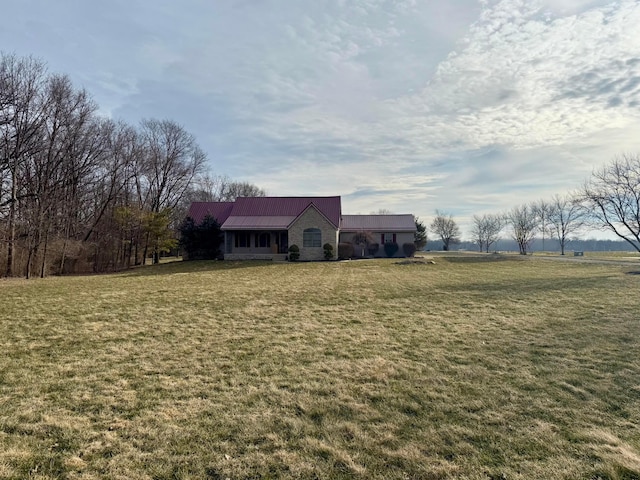 view of front of house with metal roof, a rural view, and a front yard