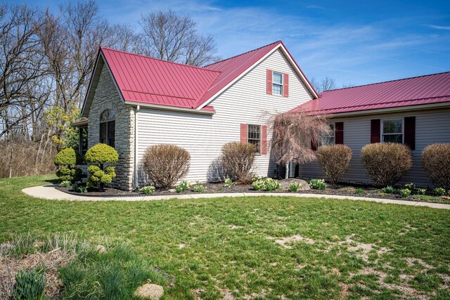 view of front of house featuring metal roof, stone siding, and a front yard