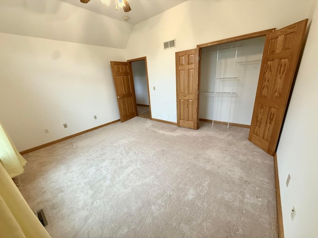 unfurnished bedroom with visible vents, baseboards, high vaulted ceiling, a closet, and light colored carpet