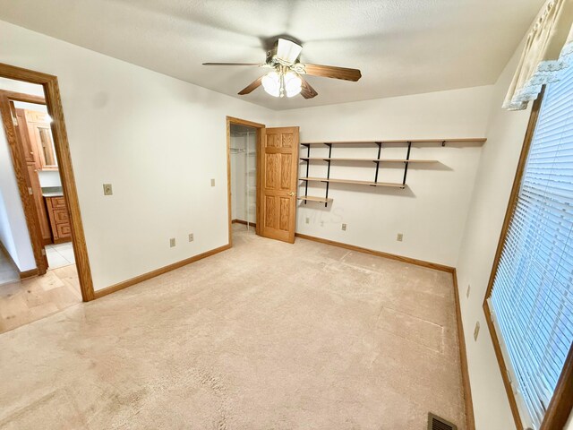 unfurnished bedroom featuring baseboards, light carpet, visible vents, and a ceiling fan