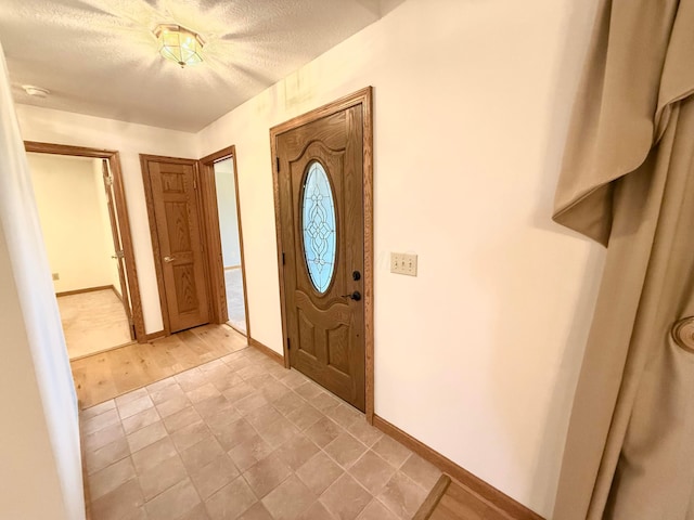 foyer entrance with baseboards and a textured ceiling