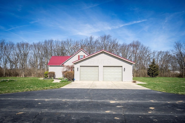 exterior space with an outbuilding, a yard, driveway, and metal roof