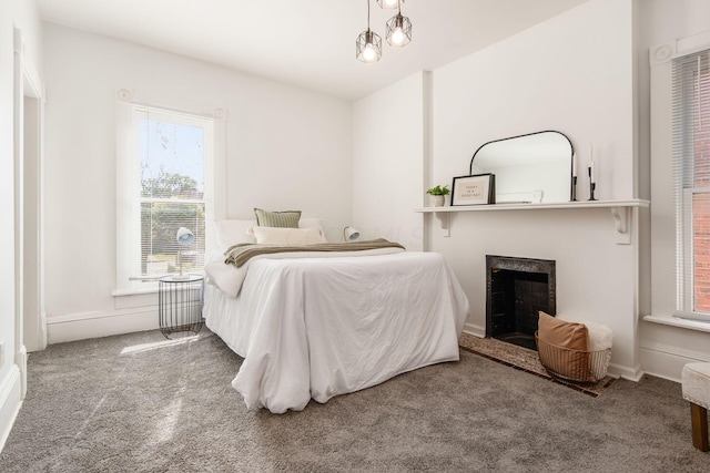 carpeted bedroom featuring a fireplace and baseboards