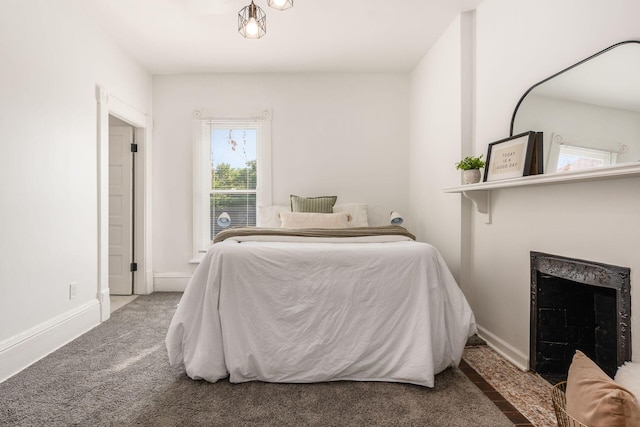 carpeted bedroom with a fireplace with flush hearth and baseboards