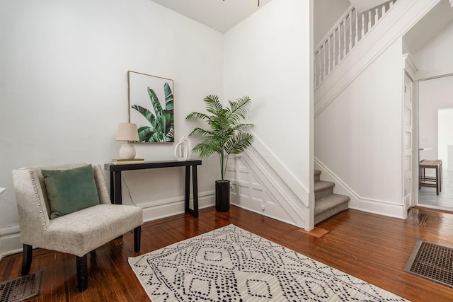 living area featuring baseboards, stairs, visible vents, and wood finished floors