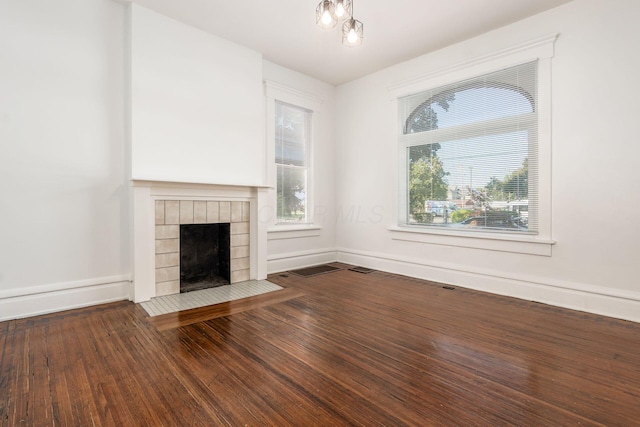 unfurnished living room with a healthy amount of sunlight, a fireplace, baseboards, and wood finished floors