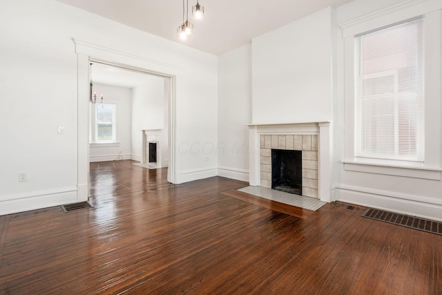 unfurnished living room featuring a fireplace with flush hearth, visible vents, and dark wood-type flooring