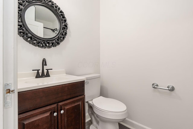 bathroom featuring baseboards, vanity, and toilet