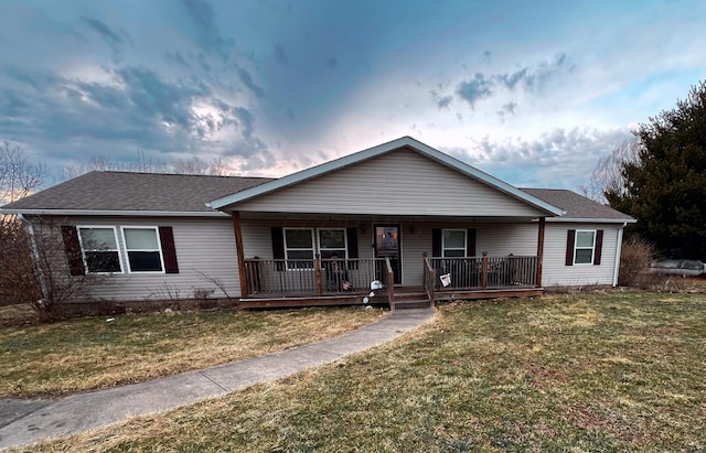 ranch-style house with a shingled roof, a porch, and a front yard