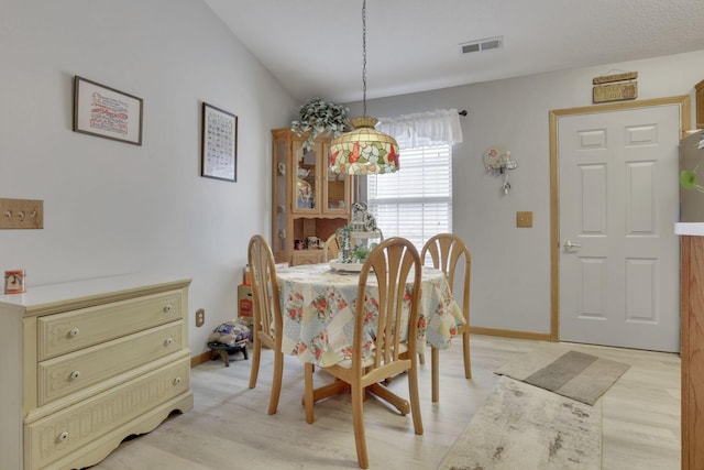 dining area with lofted ceiling, light wood-style flooring, visible vents, and baseboards