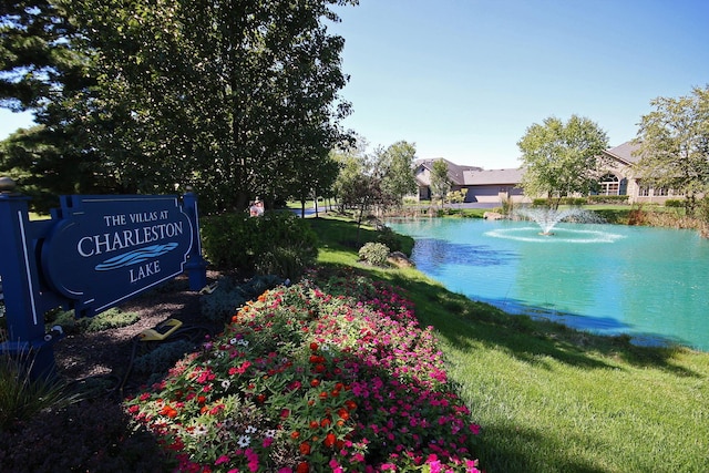 view of home's community with a water view and a lawn