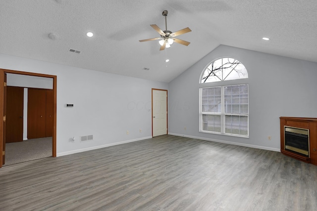 unfurnished living room featuring vaulted ceiling, wood finished floors, a glass covered fireplace, and visible vents