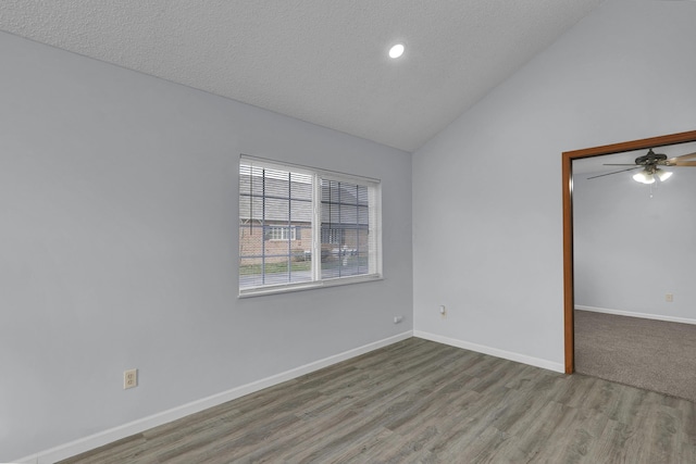 empty room featuring lofted ceiling, light wood-style floors, baseboards, and a textured ceiling