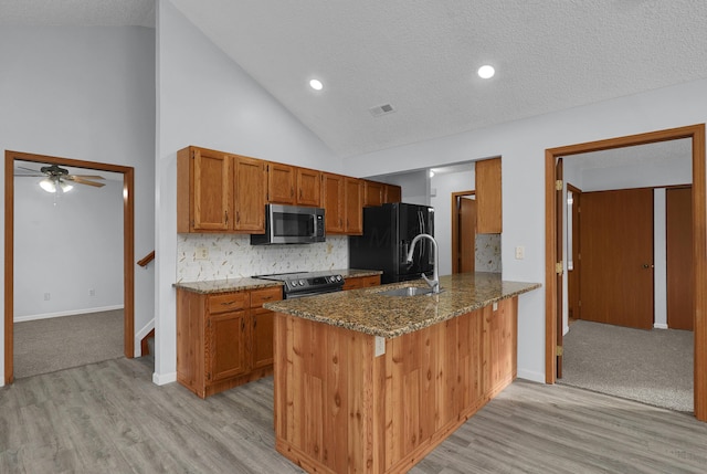 kitchen featuring a peninsula, brown cabinetry, dark stone counters, and stainless steel appliances