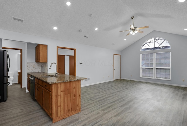 kitchen featuring a sink, visible vents, open floor plan, brown cabinets, and dishwasher