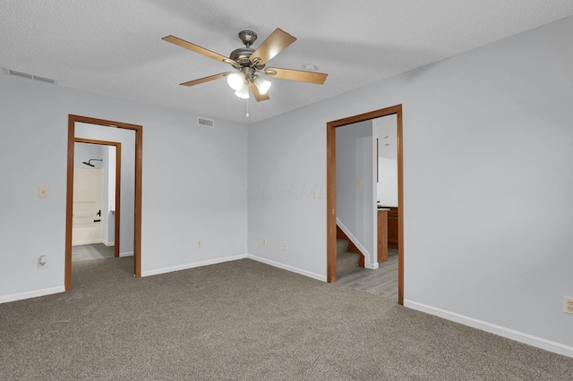 carpeted empty room with a textured ceiling, ceiling fan, visible vents, and baseboards