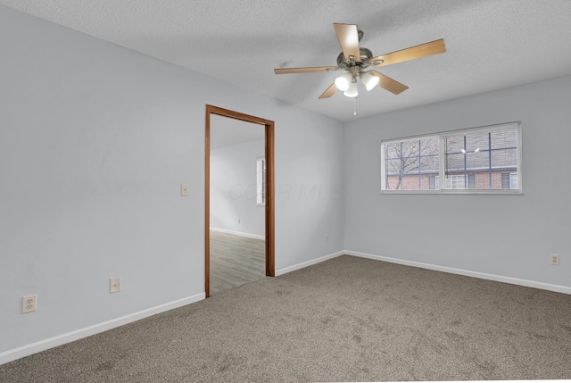 empty room with a textured ceiling, carpet, a ceiling fan, and baseboards