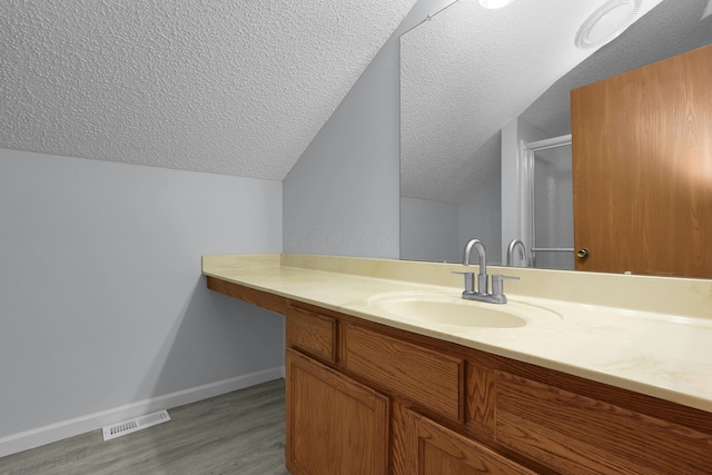 bathroom featuring visible vents, a textured ceiling, vanity, wood finished floors, and baseboards