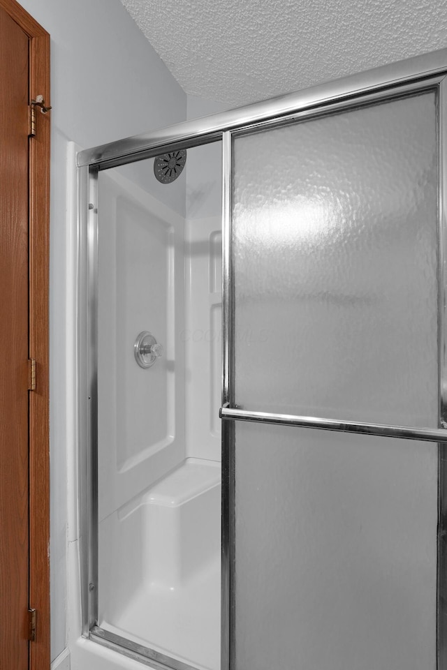 full bathroom with a stall shower and a textured ceiling