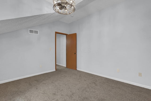 carpeted spare room featuring lofted ceiling, a textured ceiling, a notable chandelier, visible vents, and baseboards