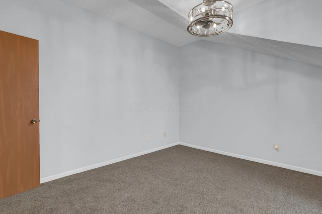 carpeted spare room featuring a chandelier, vaulted ceiling, a textured ceiling, and baseboards