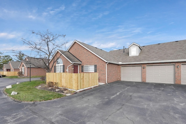 view of side of property with a garage, aphalt driveway, and brick siding