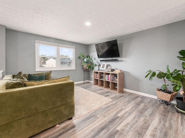 living room featuring a textured ceiling, baseboards, and wood finished floors