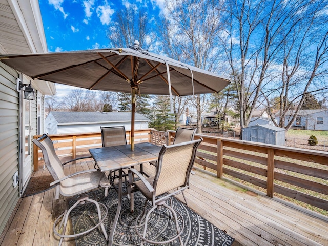 wooden deck featuring outdoor dining area, an outdoor structure, and a shed