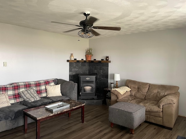 living area with a wood stove, a textured ceiling, a ceiling fan, and wood finished floors