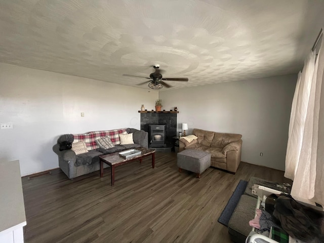 living room featuring visible vents, a ceiling fan, dark wood-style flooring, a wood stove, and a textured ceiling