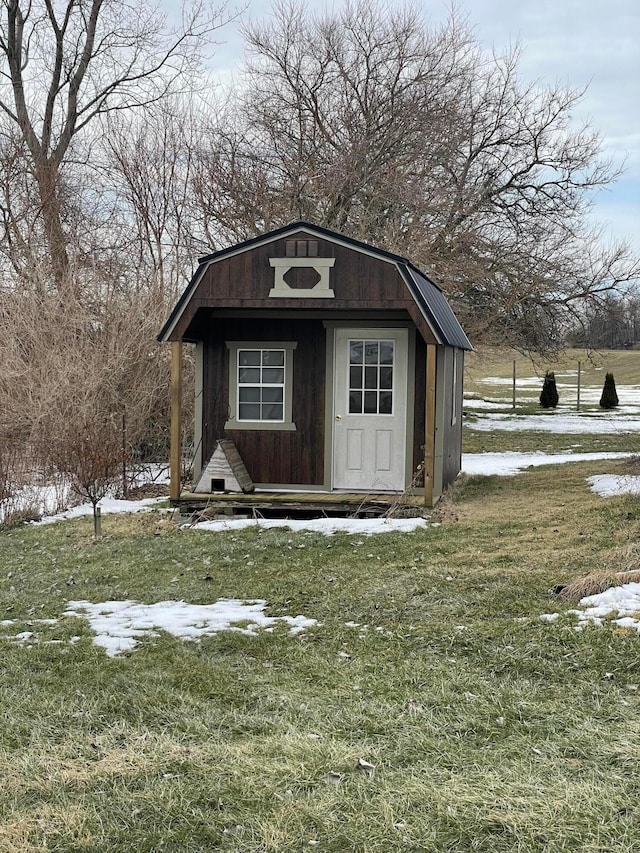 snow covered structure featuring a yard and an outdoor structure