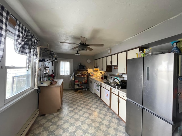 kitchen with freestanding refrigerator, white cabinets, light countertops, and light floors