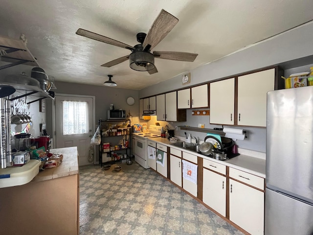 kitchen with a textured ceiling, stainless steel appliances, white cabinets, light countertops, and light floors